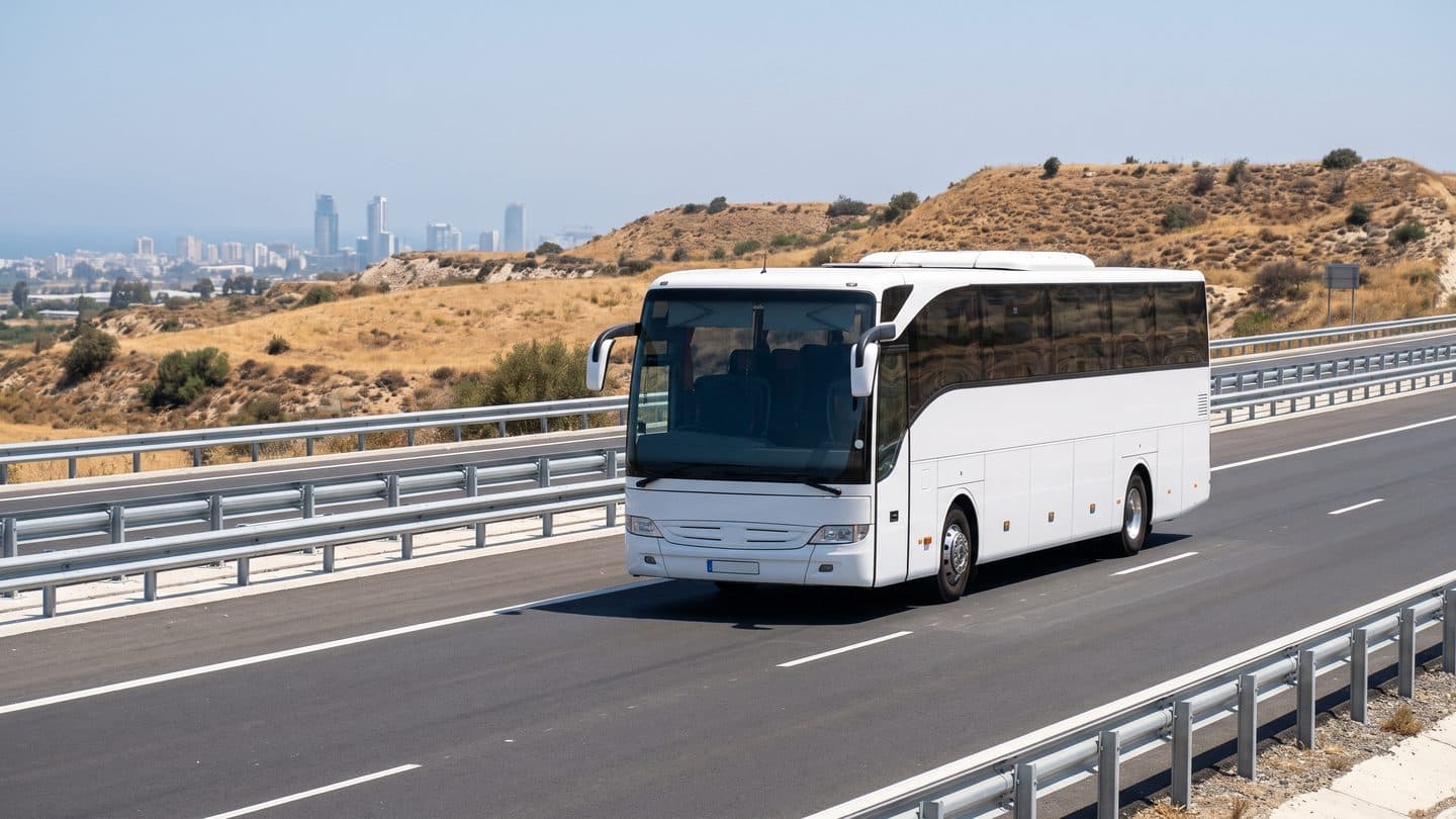 Ein Überlandbus wartet in einer Haltebucht an einer leeren Schnellstraße in trockenen Hügeln